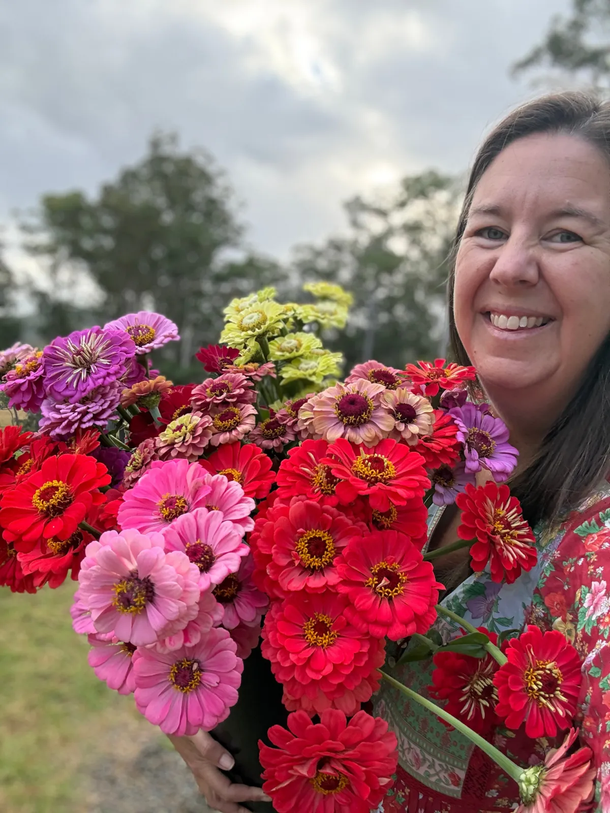 Natalie, Founder Cut Flower Planner holding a armload of zinnias