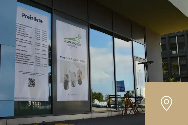 Außenansicht vom Friseursalon Glücksschere mit Preisübersicht im Fenster
