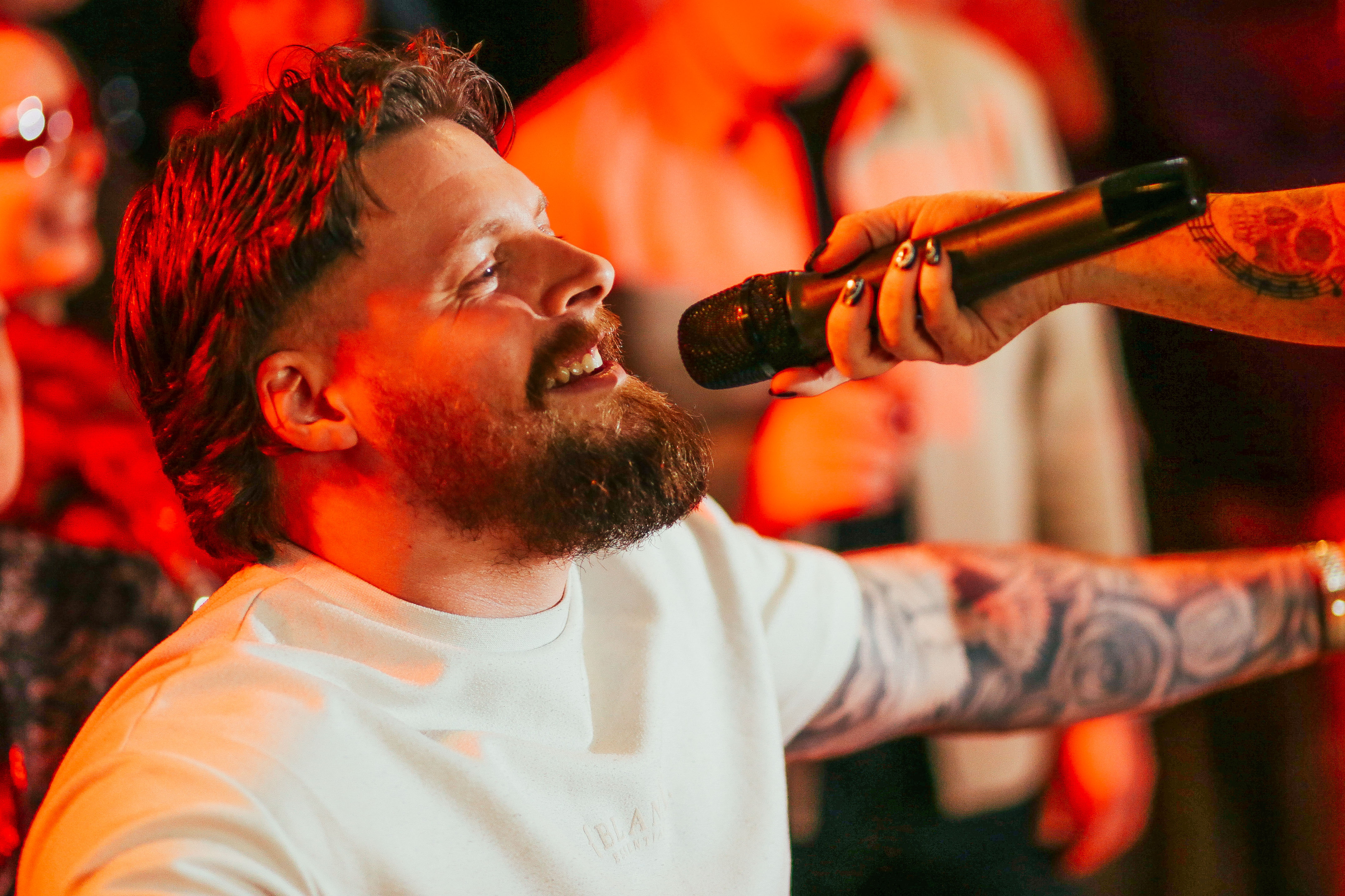 Fans singing karaoke under neon lights at Saturday Night Rodeo