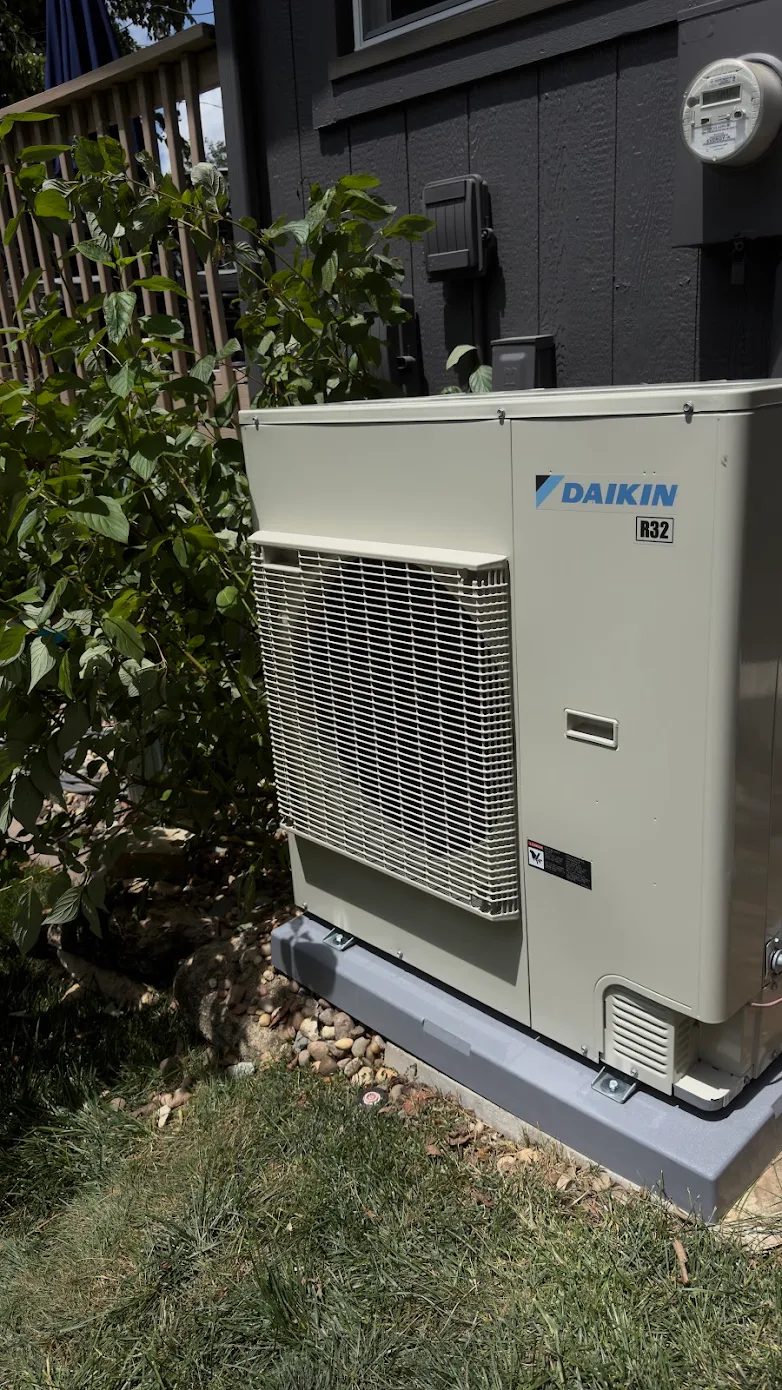A modern Daikin R32 multi-zone heat pump system installed outdoors on a specialized mounting pad with proper landscape integration in Kansas City.