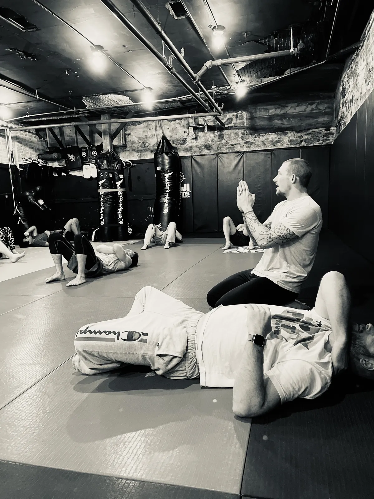 A coach kneeling beside participants during a group floor-practice session