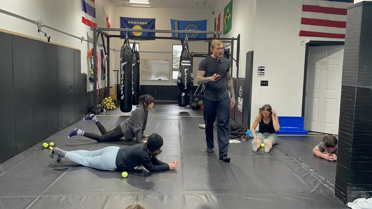 Group coaching on the mats, with participants practicing floor positions and using mobility balls