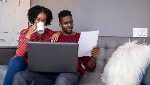 A man an woman on the couch reviewing an electricity bill.