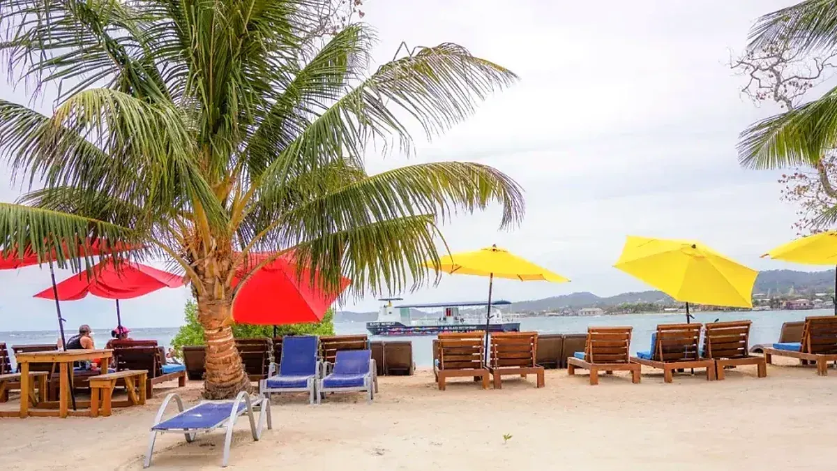 Roatan cruise day beach experience with lounge chairs, palm trees, and turquoise water