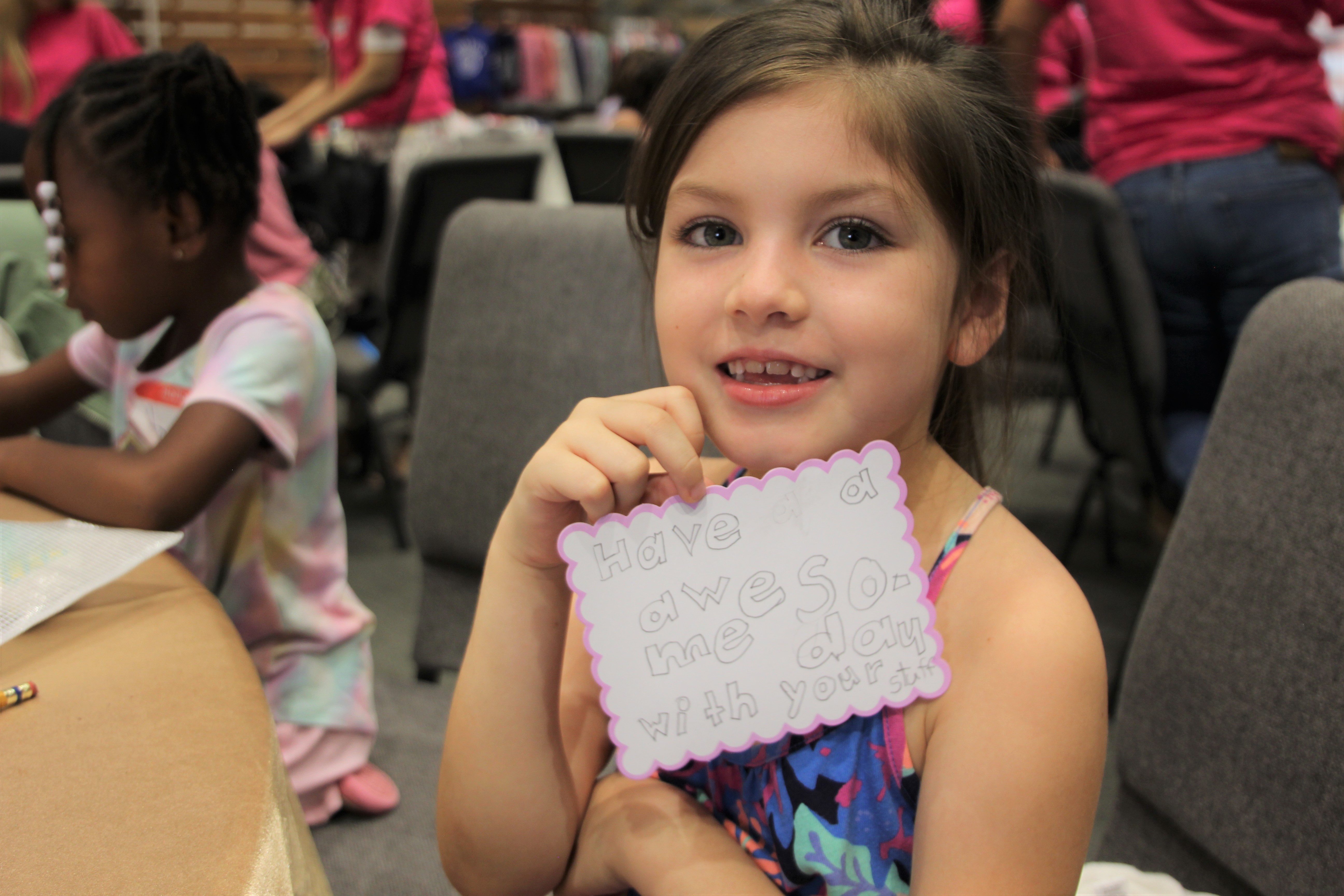Child writes A in green sand