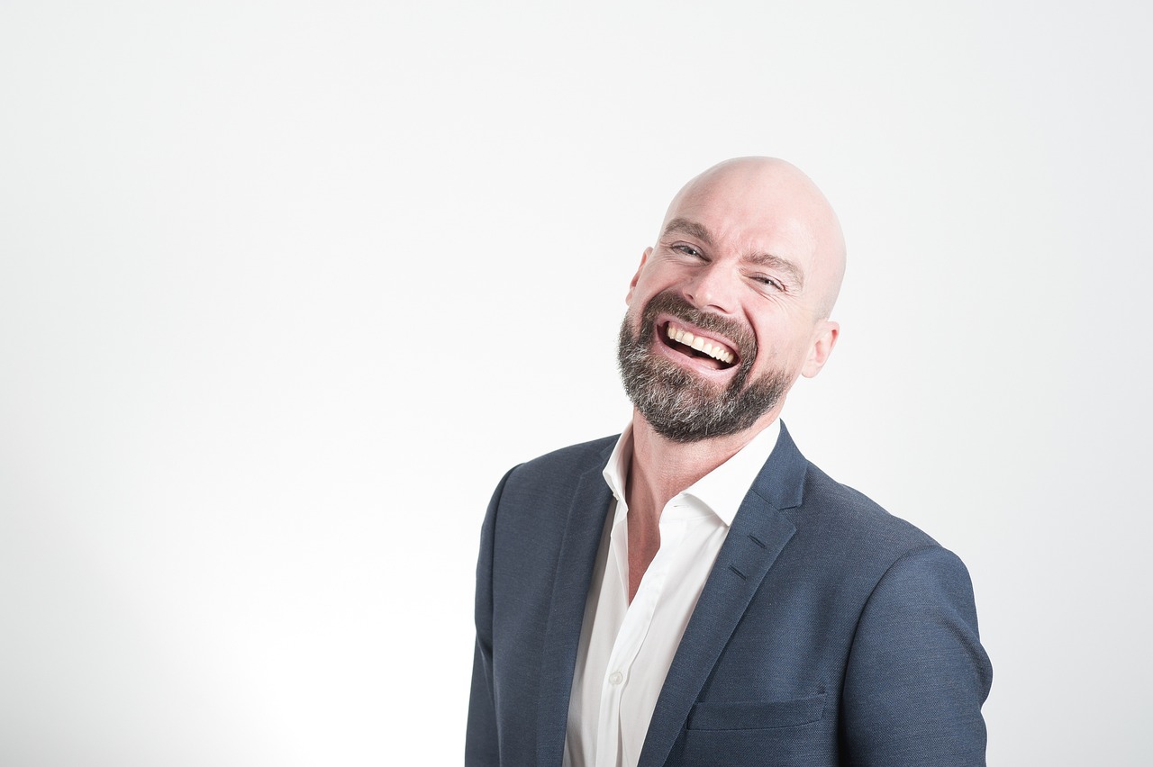 Man in suit in front of white background laughing
