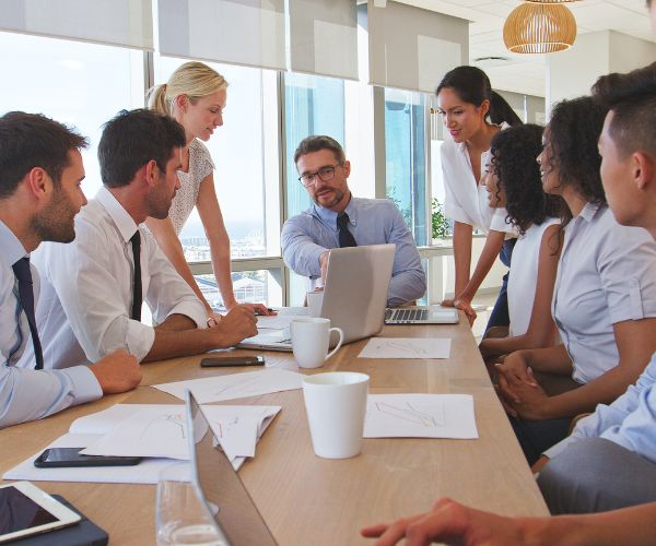 A collaborative team of diverse professional leaders working together constructively in a spacious, modern corporate conference room.
