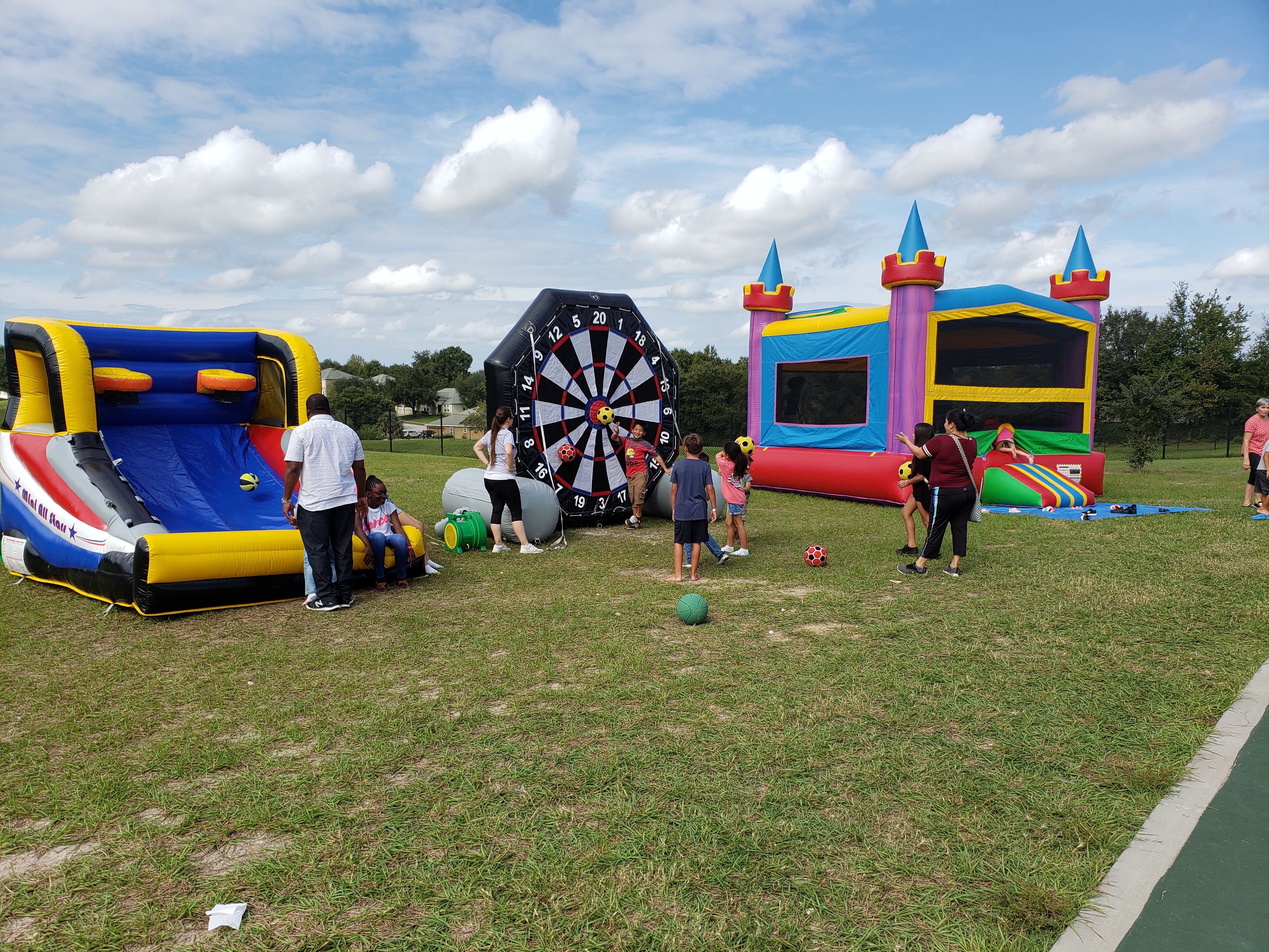 Kids enjoying a bounce house at a family-friendly event with attendants nearby