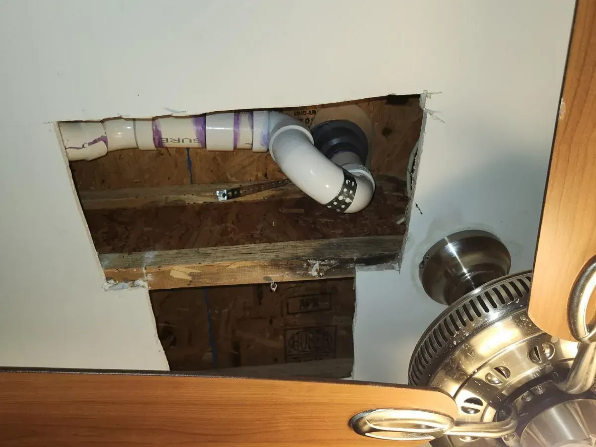 Installed blue garbage disposal unit under kitchen sink with connected drain pipes, electrical wiring, and cabinet interior.