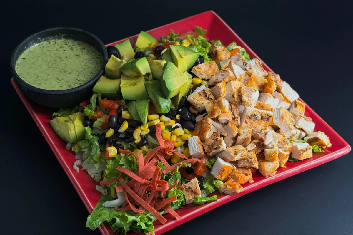 Mexican Chopped Salad- Chopped romaine and iceberg lettuce with flame-grilled chicken, avocados, tomatoes, red bell pepper, black beans, black olives, roasted corn, and crispy tortilla chips. Served with cilantro-lime dressing on the side.