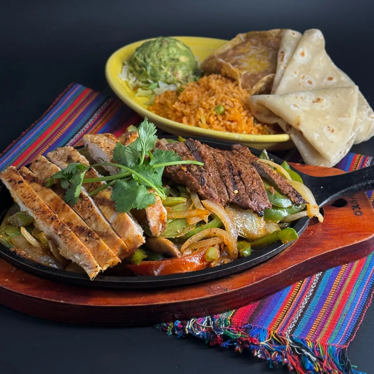 Combo Fajitas: Chicken and Beef Flame-grilled Chicken and Beef with fresh bell peppers mushrooms, onions, and tomatoes on a sizzling skillet. Served with frijoles de la olla, guacamole, and Arroz Mexican