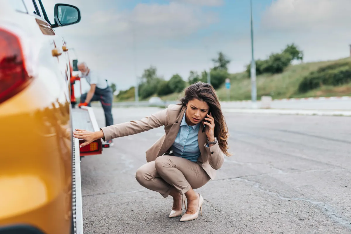 women with worried look in her face, making a call while her car is being loaded on the back of an affordable towing Laredo's tow trucks