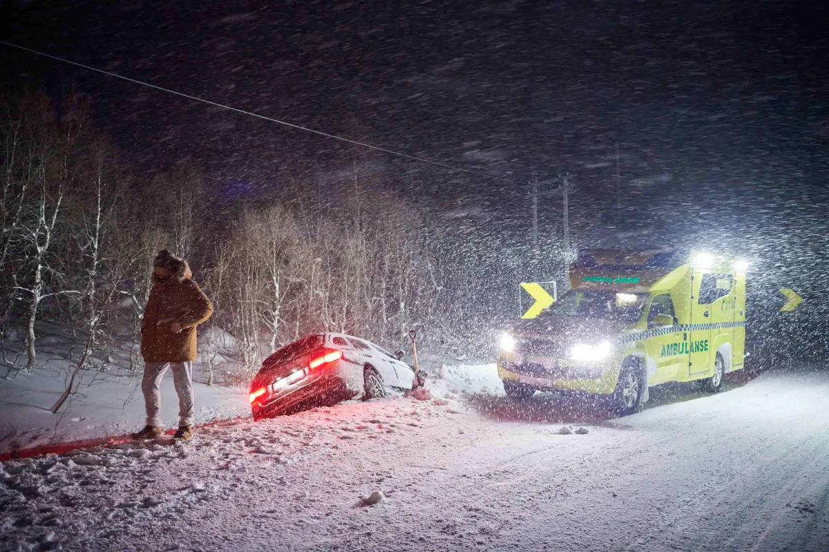 person standing away from the scene of a car that went off the side of the road as an ambulance arrives on the scene in a dark gloomy Mentor Ohio night
