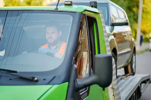 A male technician from affordable towing mentor on a tow job with an suv in the back