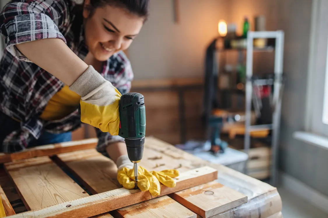 Homeowner using power drill for renovation work on wood - home improvement project adding value that requires homeowners insurance update in Wayne County