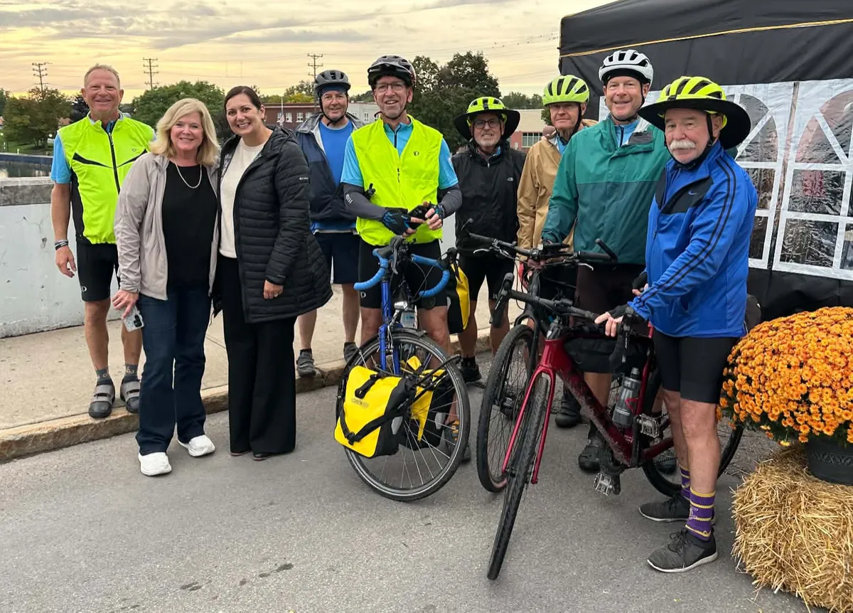 Members of the Bicycle Boys pose with their bicycles alongside community members during their stop at Autumn on the Erie in Newark, New York.