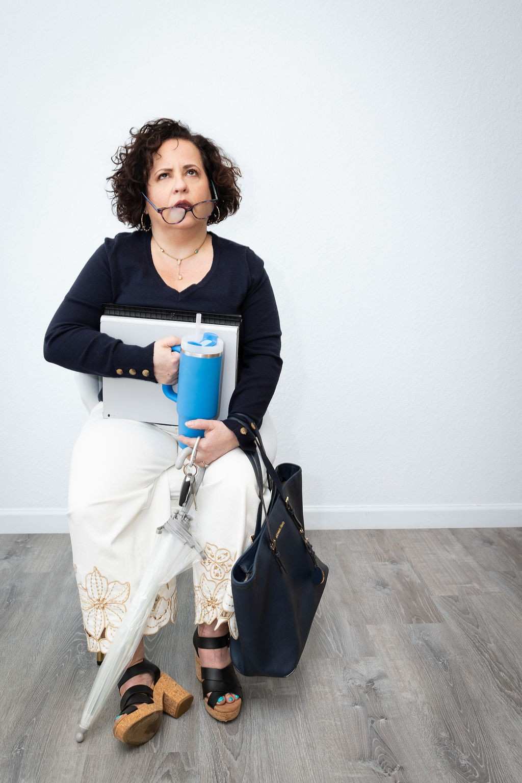Tracie Merwitzer, certified hypnotherapist in Asheville NC, humorously juggling a laptop, water bottle, umbrella, purse, and glasses to illustrate the overwhelm women carry every day.