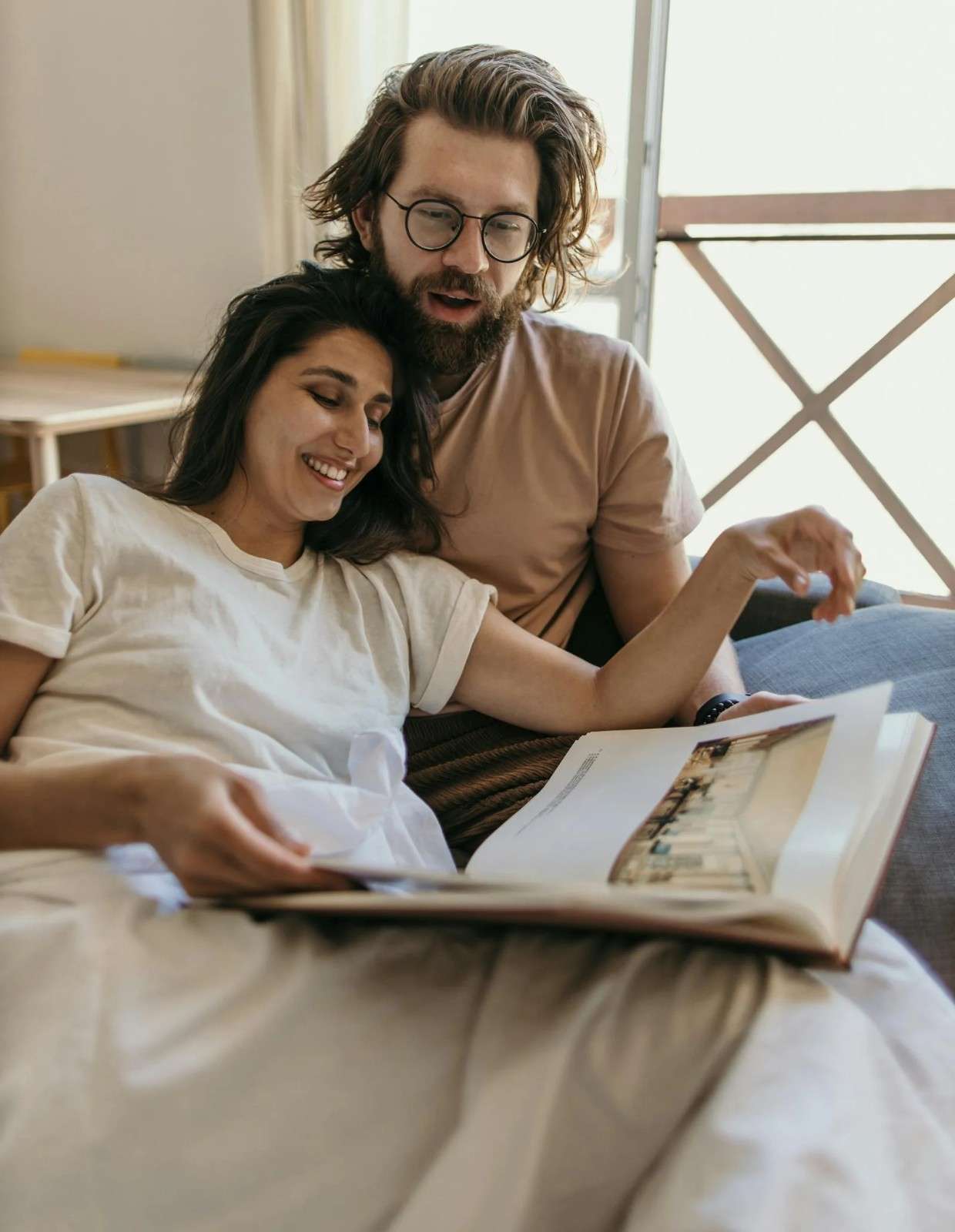Couple relaxing together on a couch looking through a book, representing connection and partnership during the fertility journey.