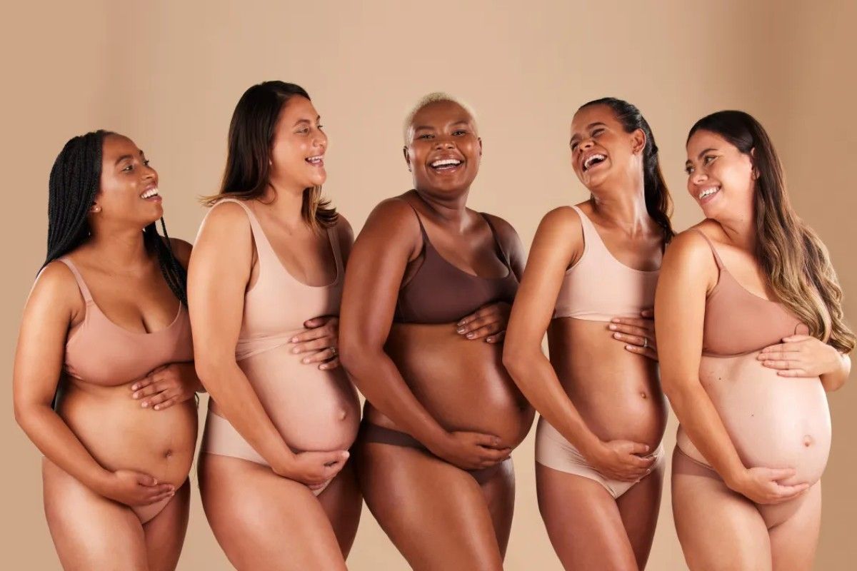 Group of diverse pregnant women laughing together, representing the supportive community and inclusive approach of hypnobirthing and fertility care.
