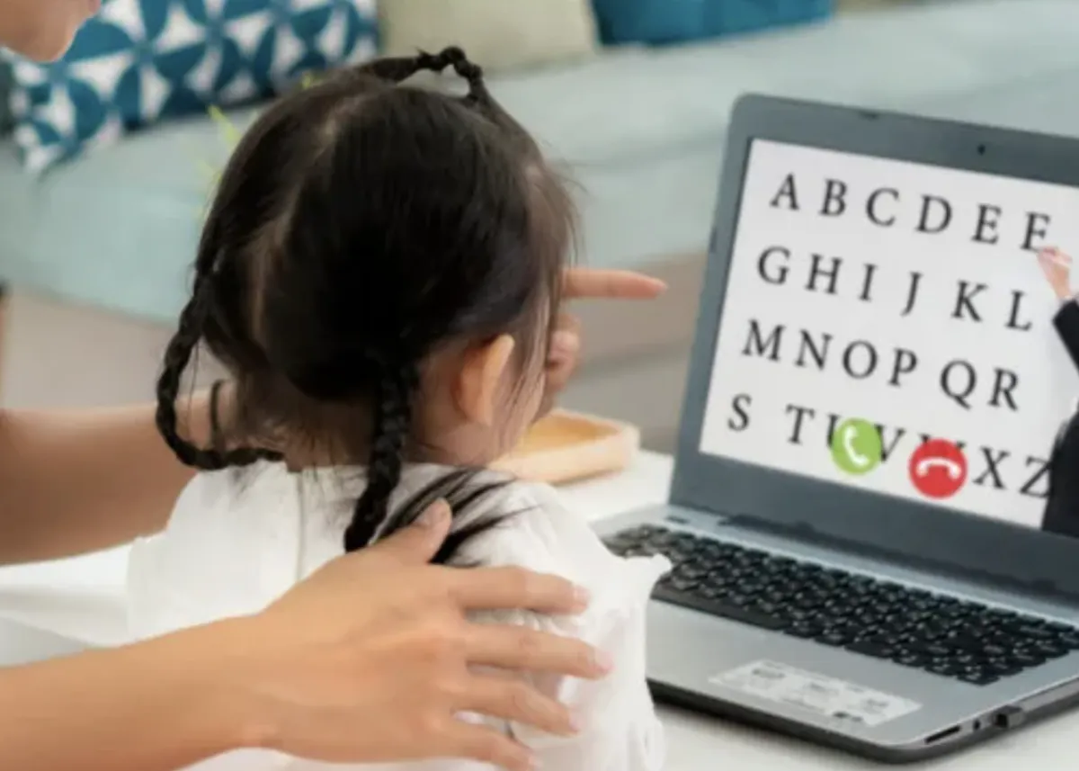 Child with headset smiles as he engages with laptop