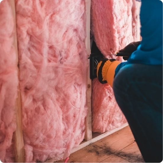 Insulation contractor installing thermal batt insulation in wall cavities for energy code compliance