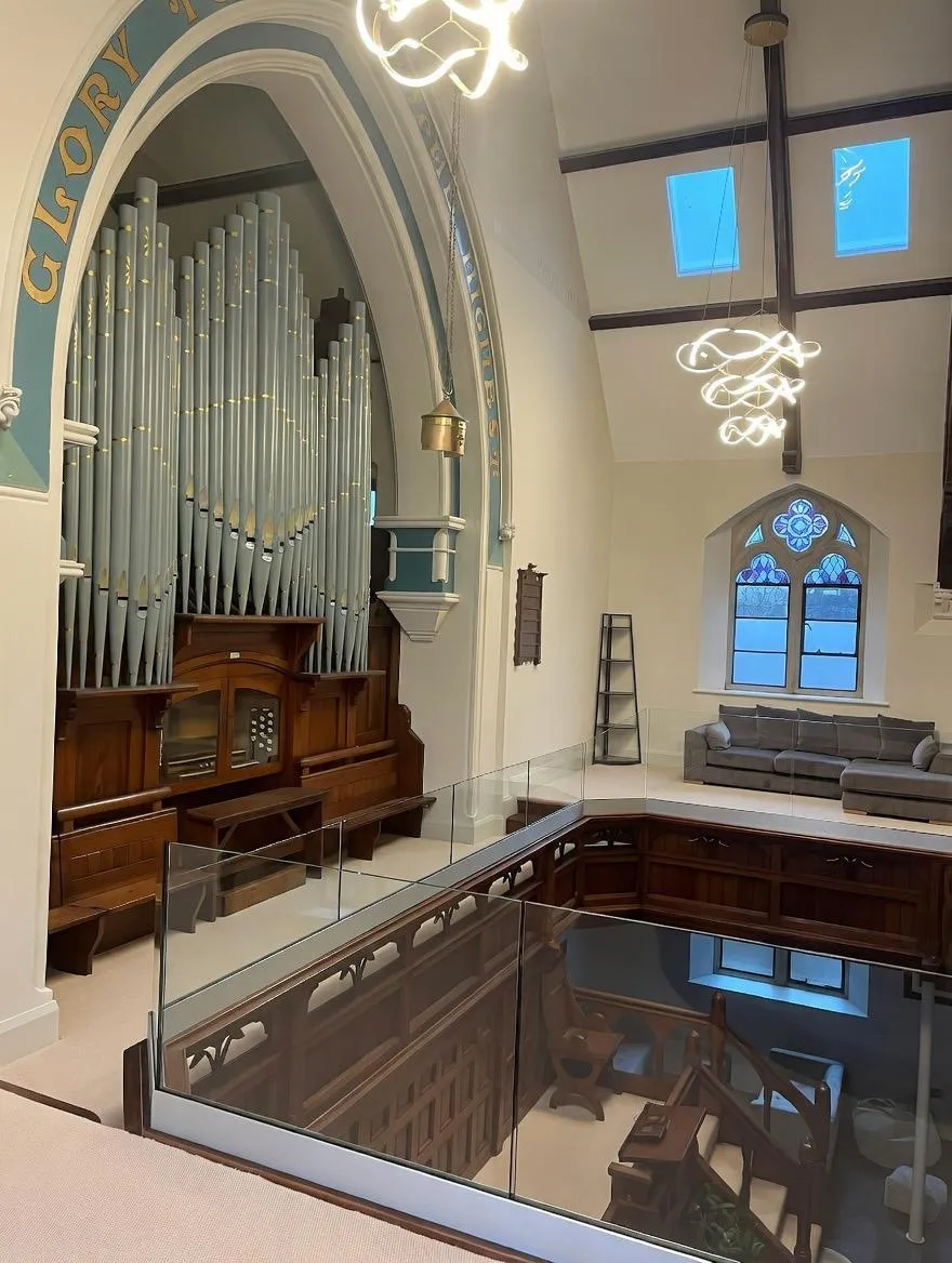 Frameless glass balustrade installed in church conversion preserving original organ and interior features