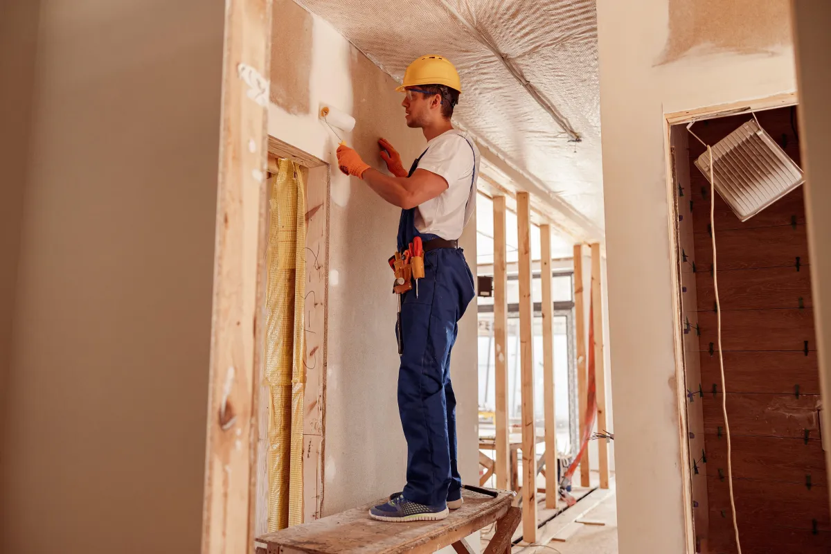 male-builder-painting-wall-in-house-under-construction