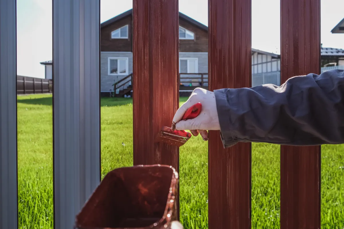 a-man-paints-an-iron-fence-in-the-garden