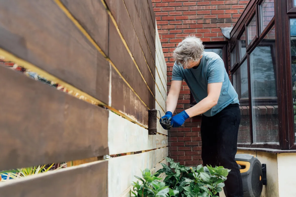 young-man-worker-paints-with-roller-a-wooden-board