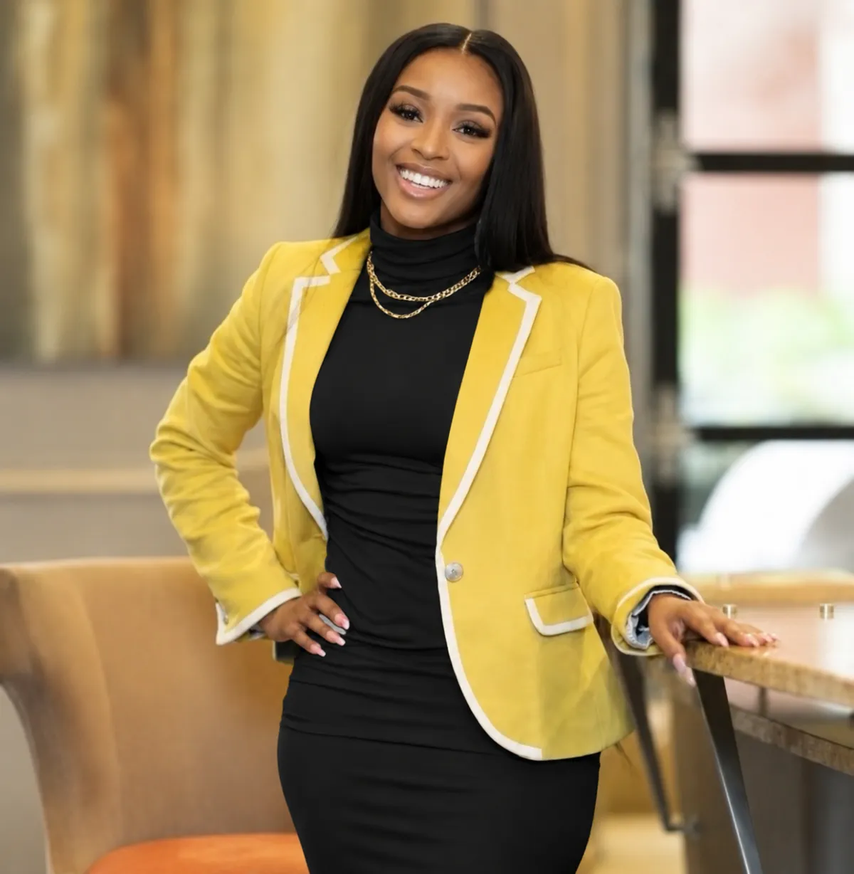 Professional woman in white blazer sitting in front of a bookshelf