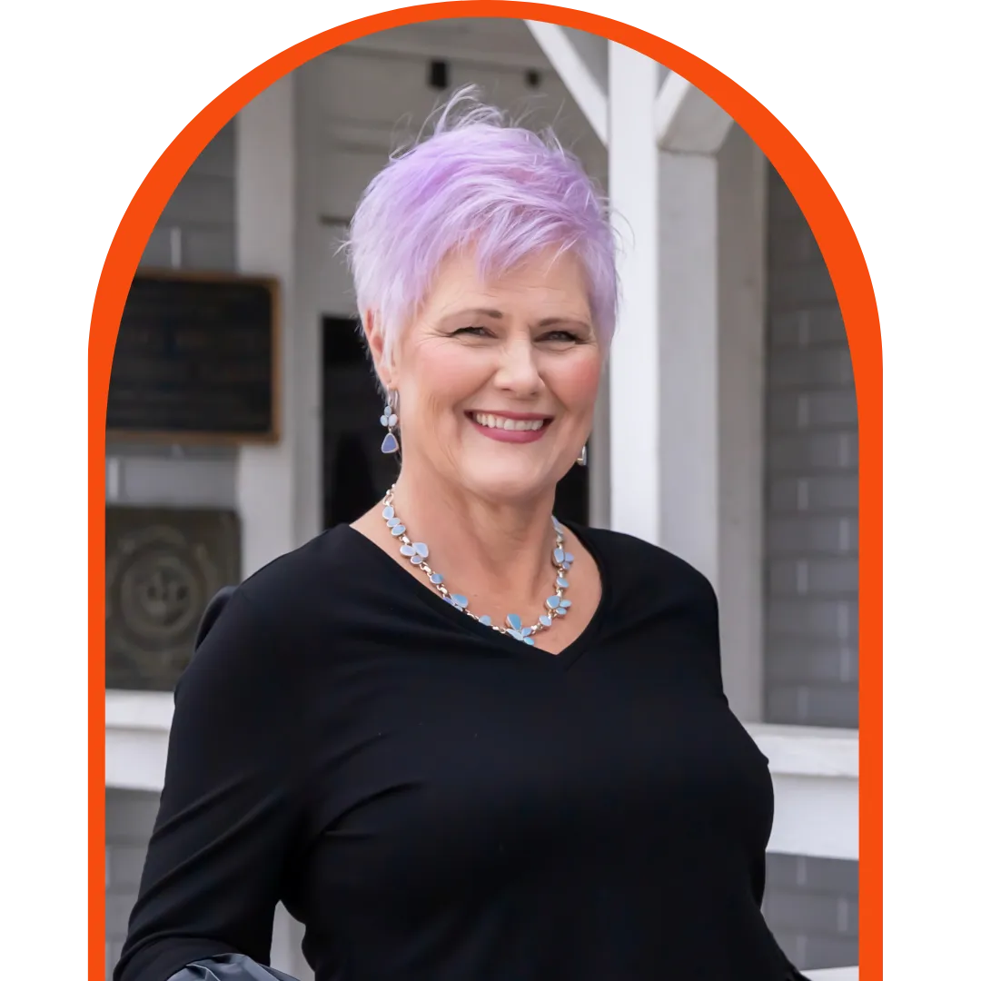 Nancy Hicks, Founder of Sell Pop's Place, stands in front of a grey and white home