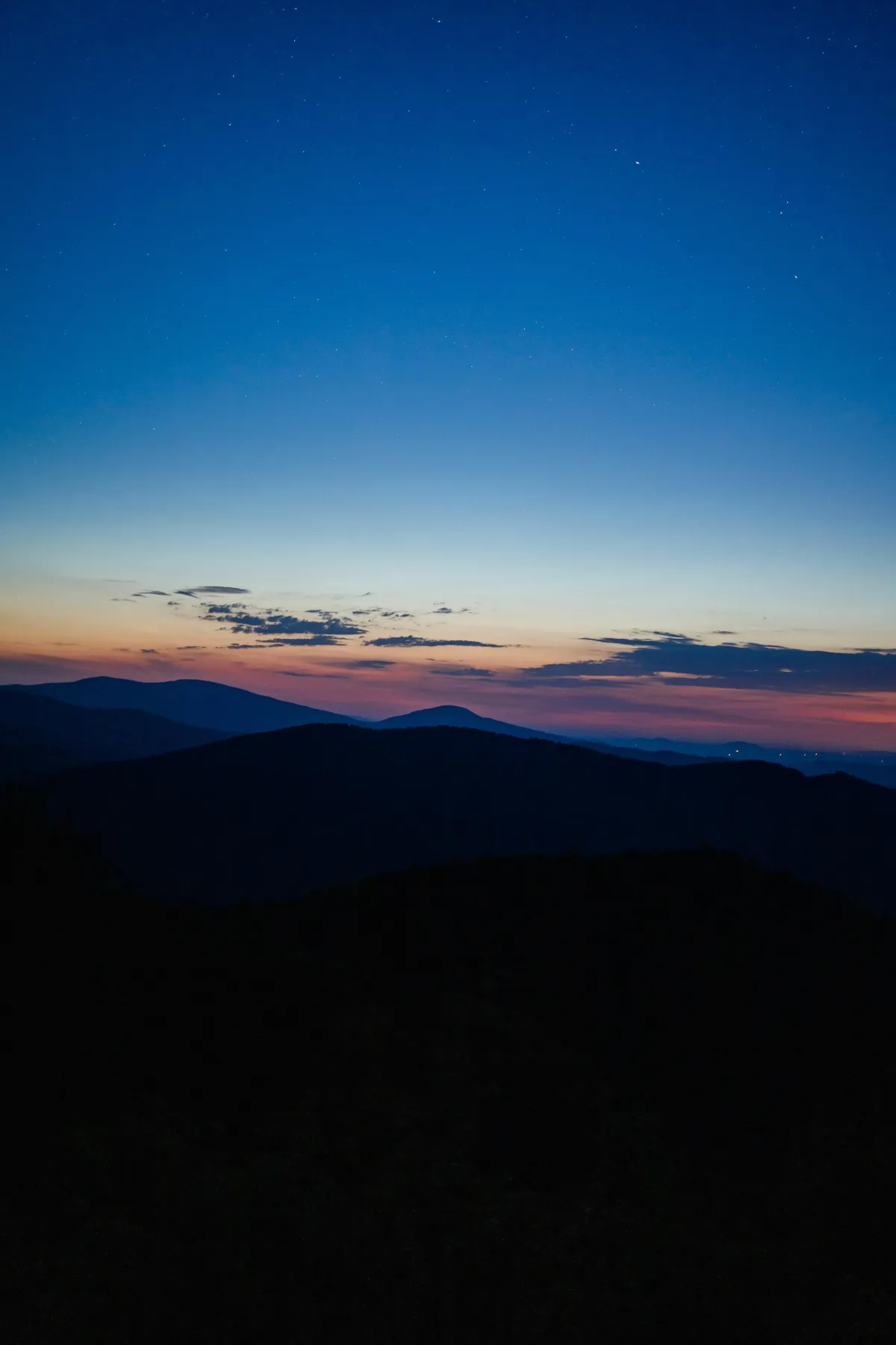 Mountain ridges silhouetted against a twilight sky with layered clouds, representing the journey of professional development and elevated perspective gained through The Consulting Lab inc.'s (TCLi) Academy courses and programs