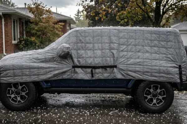 Hail Shield fully deployed over a vehicle with dark storm clouds in the background — Caption: "Hail Shield deploys in minutes — before the first hailstone falls."