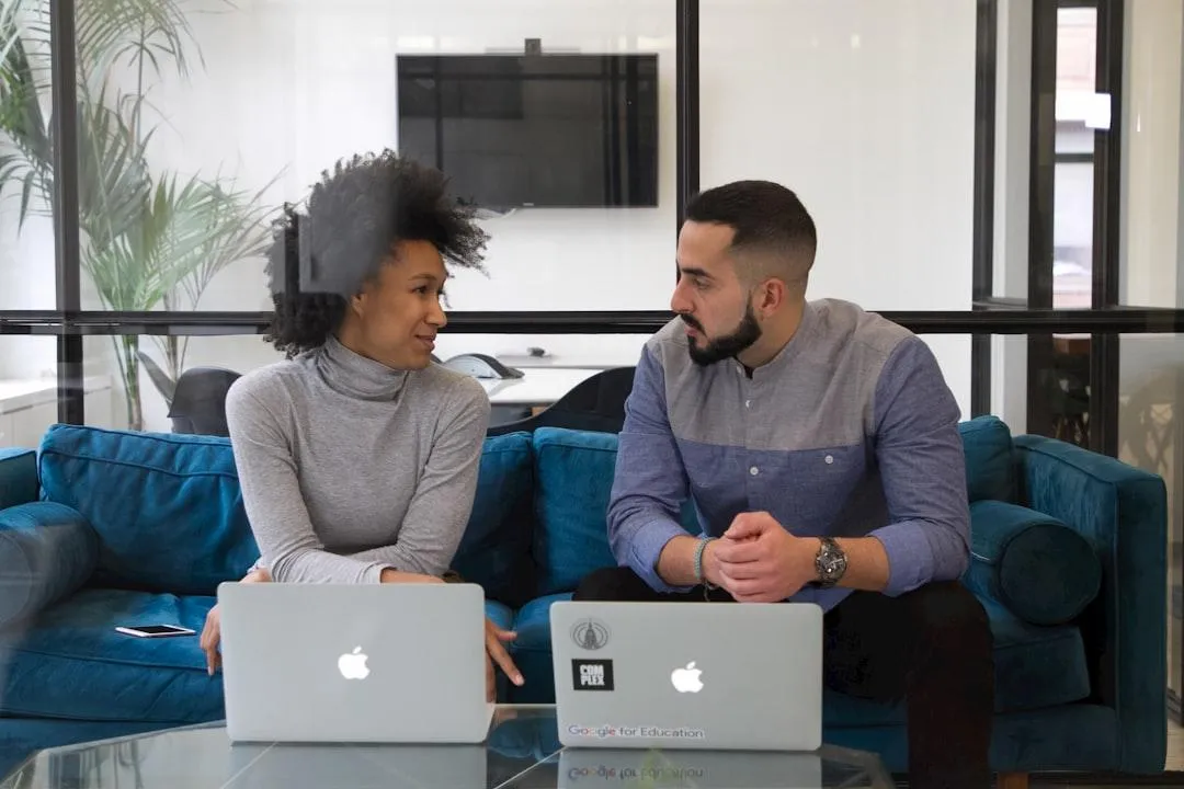 Three entrepreneurs collaborating around a laptop in a bright, modern co-working space