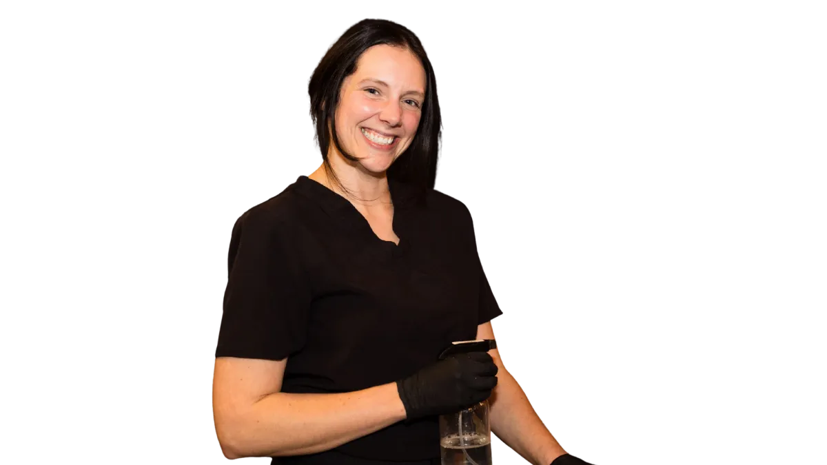 DayMaker Cleaning Co. Cleaner standing with spray bottle smiling in black uniform