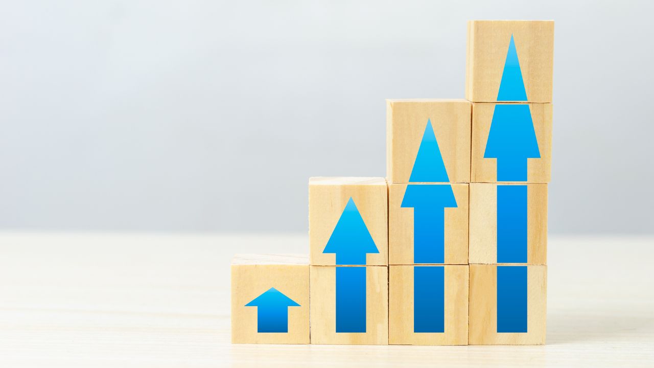 Person using calculator at desk with computer charts.