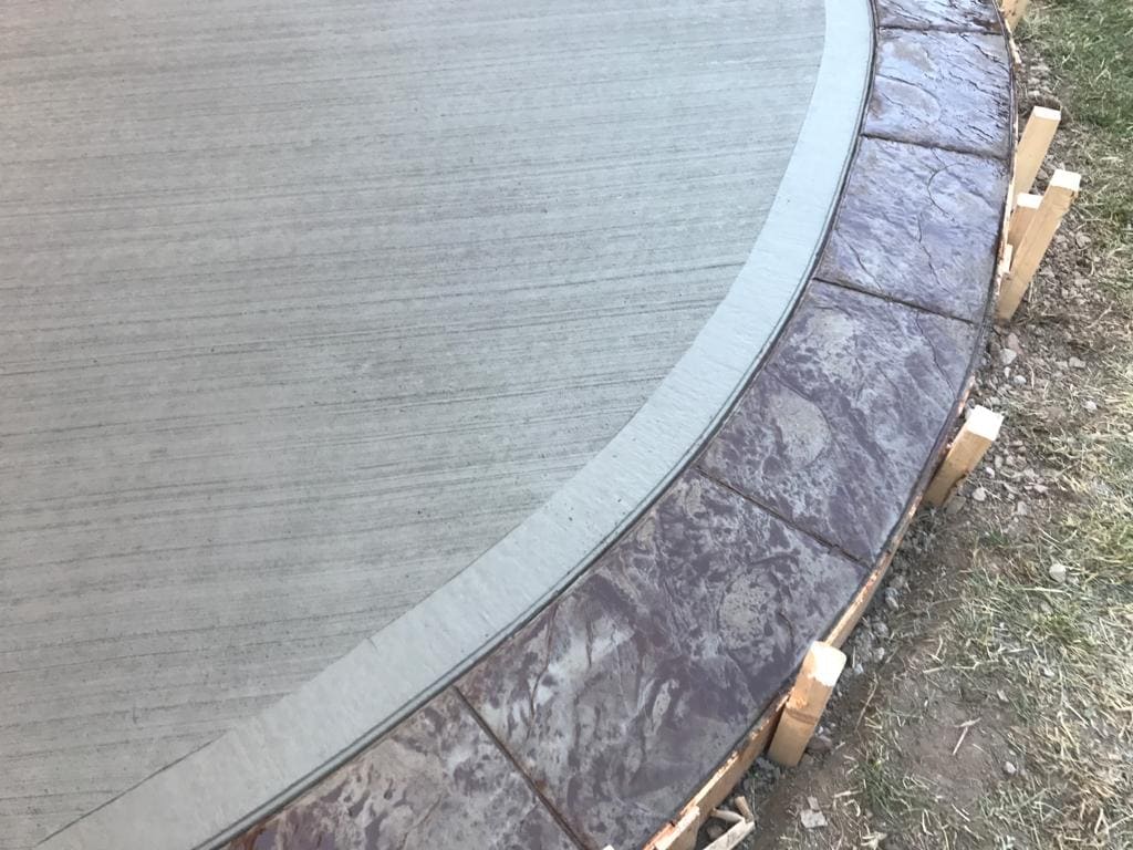 Curved concrete front steps and landing leading to a home’s entrance, featuring clean lines and a light grey finish. The custom-shaped design adds a modern upgrade to the home's entryway.
