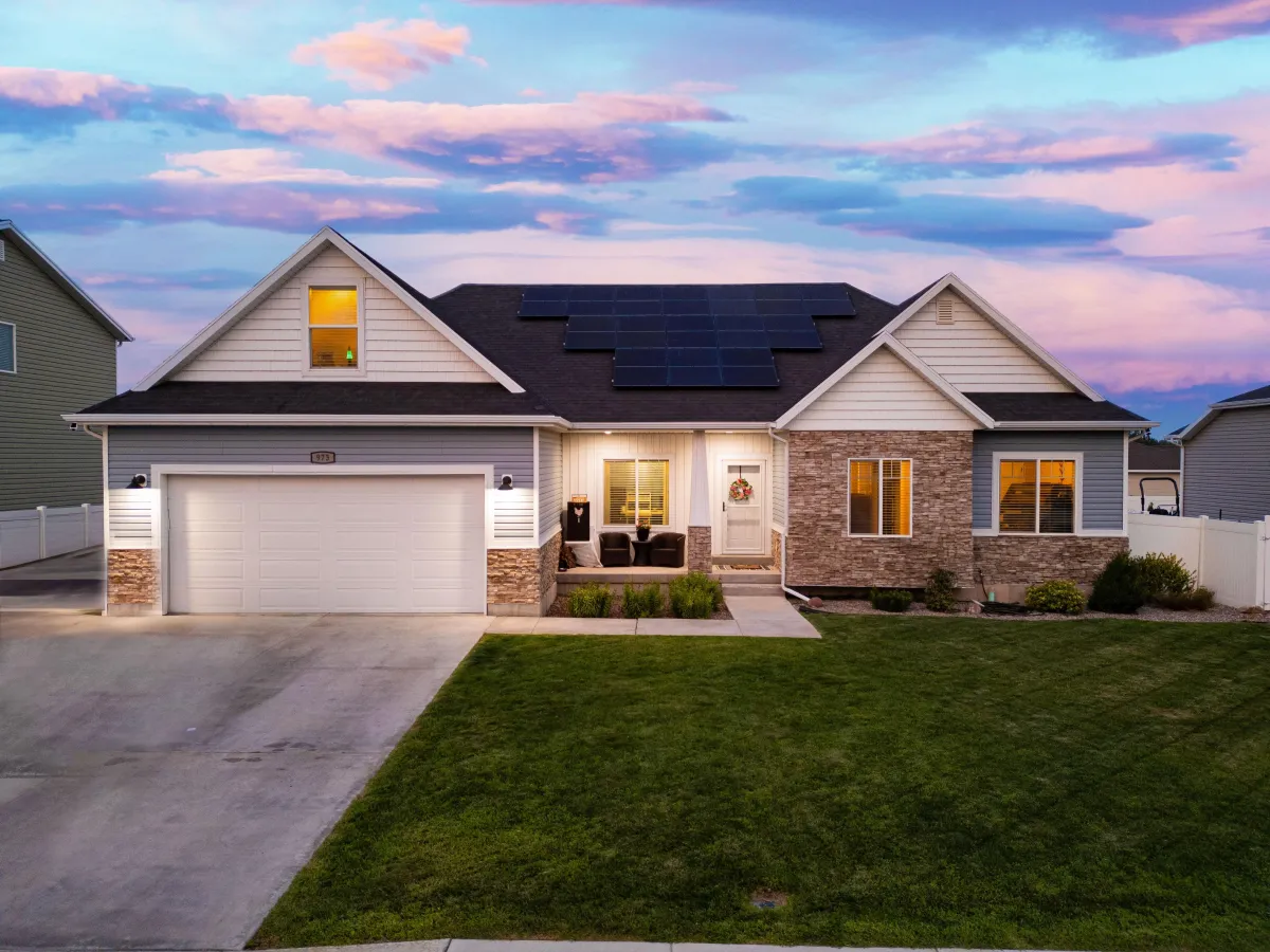 beautiful stucco stone home in vernal utah with lit windows and sunset