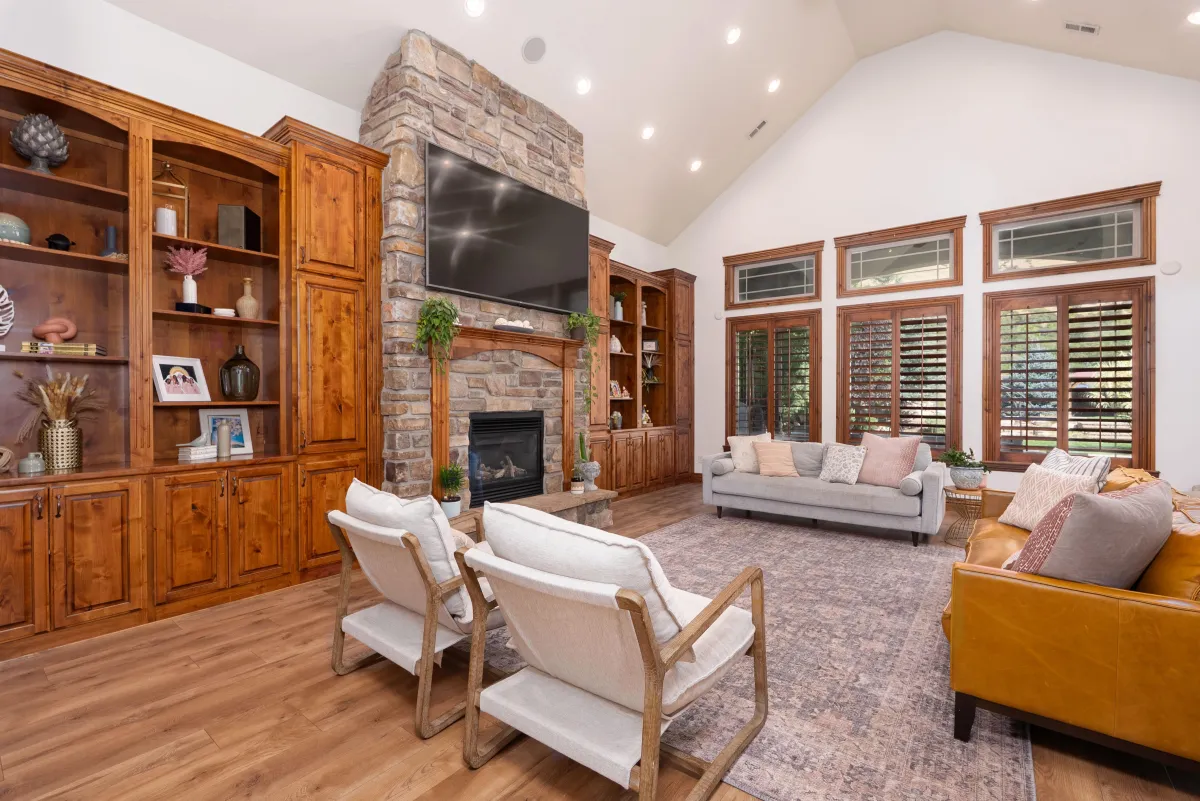 Luxury Utah home living room with stone fireplace, vaulted ceilings, and custom wood cabinetry