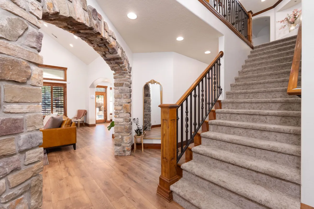 Luxury Utah home interior with stone archway, wood floors, and elegant staircase
