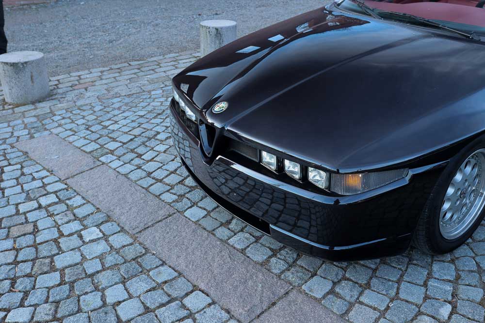 thee headlights on a Alfa Romeo RZ on a parking