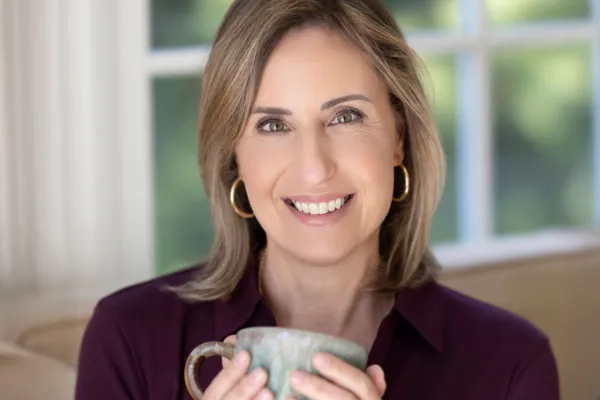 Midlife woman holding a mug and smiling, representing gut health support during perimenopause