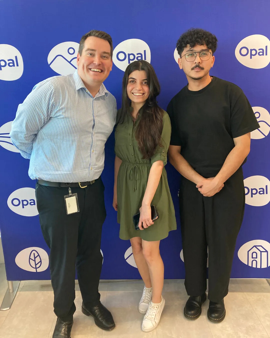 A group photo of colleagues posing in front of a backdrop at an Opal Healthcare event