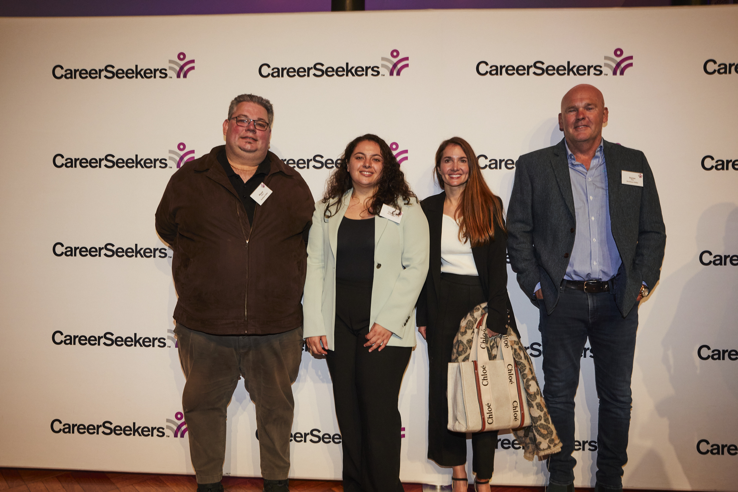 A large group of colleagues posing in front of a backdrop at a CareerSeekers event