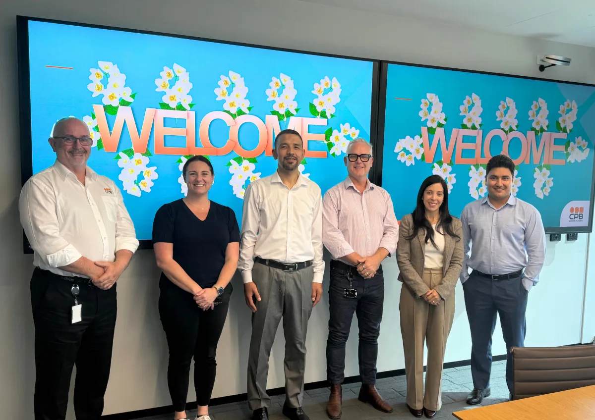 A group of colleagues and CareerSeekers community standing together in front of a presentation screen at an End of Placement Presentation