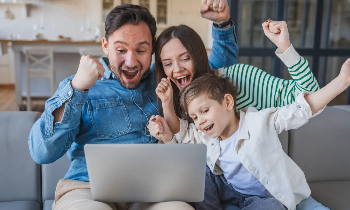 Happy family celebrating with laptop after learning confident parent advocacy skills for IEP meetings.