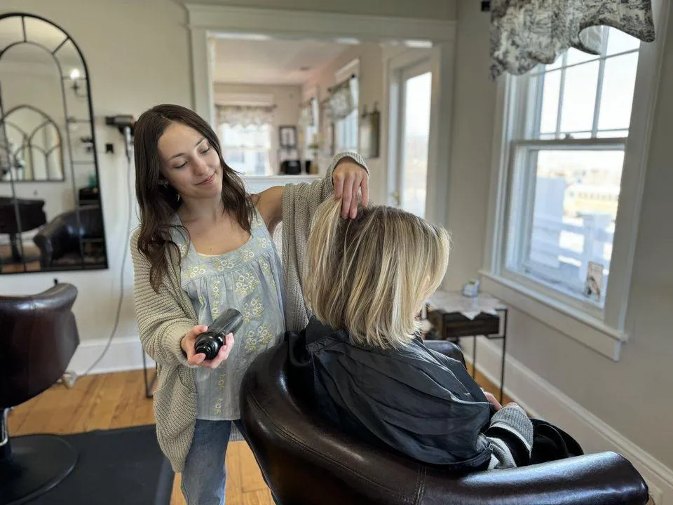 Owner, Zoe Zimmerman, smiling as she works on a customer's hair.