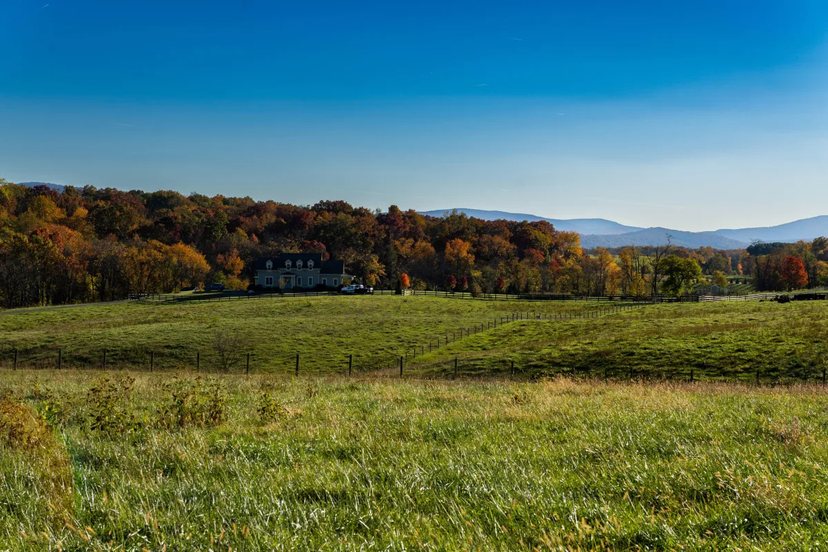Scenic view of Briarmead Farm in Front Royal, Virginia, featuring lush fall foliage, a farmhouse, fenced pastures, and rolling hills, home to organic, grass-fed cattle.