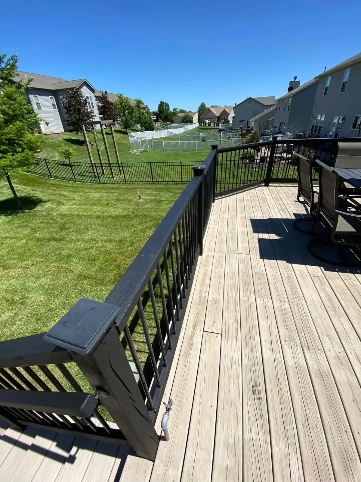 Deck railing with black metal handrail installed in O’Fallon, MO – long view of custom-built platform.