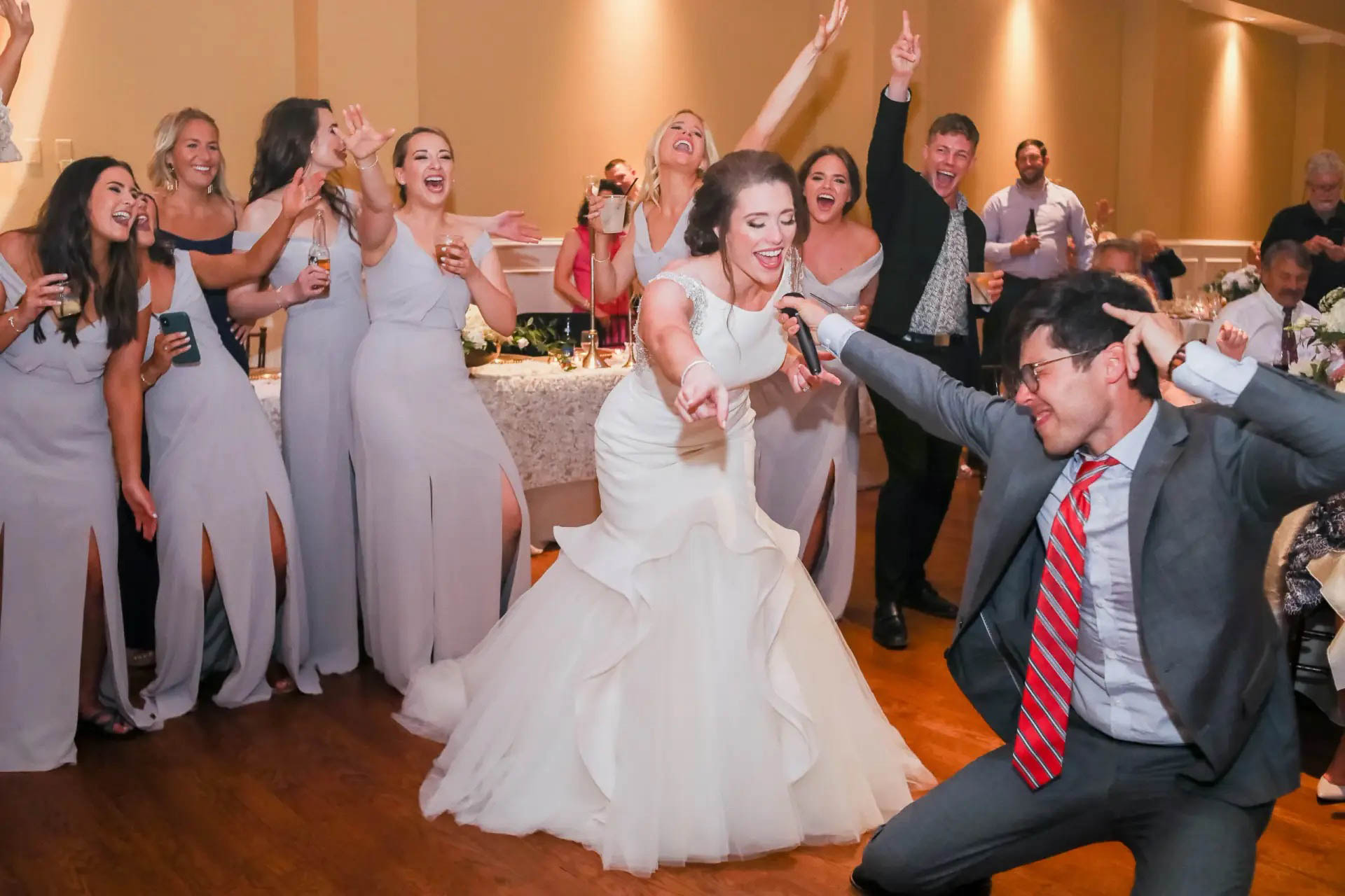 Bride and groom singing and dancing with guests at packed KC, MO wedding DJ reception